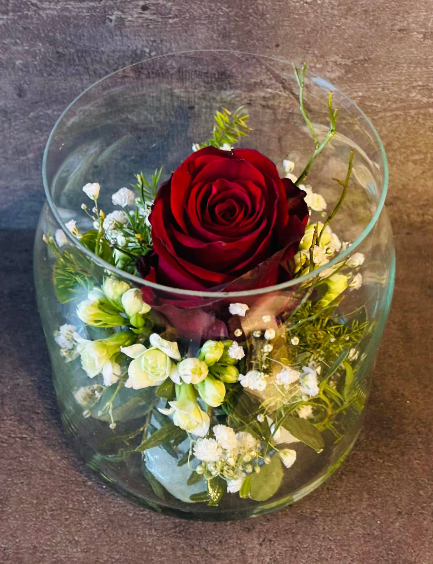 Rote Rose im Glas mit Schleierkraut